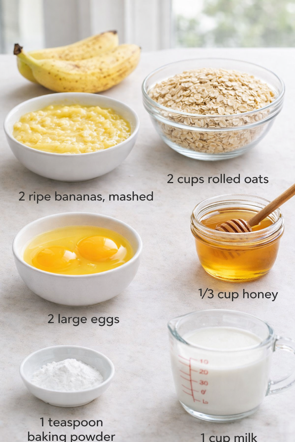 Measured ingredients arranged for Protein Banana Oat Breakfast Squares: 2 ripe bananas, mashed, 2 large eggs, 2 cups rolled oats, 1/3 cup honey, 1 cup milk, 1 teaspoon baking powder